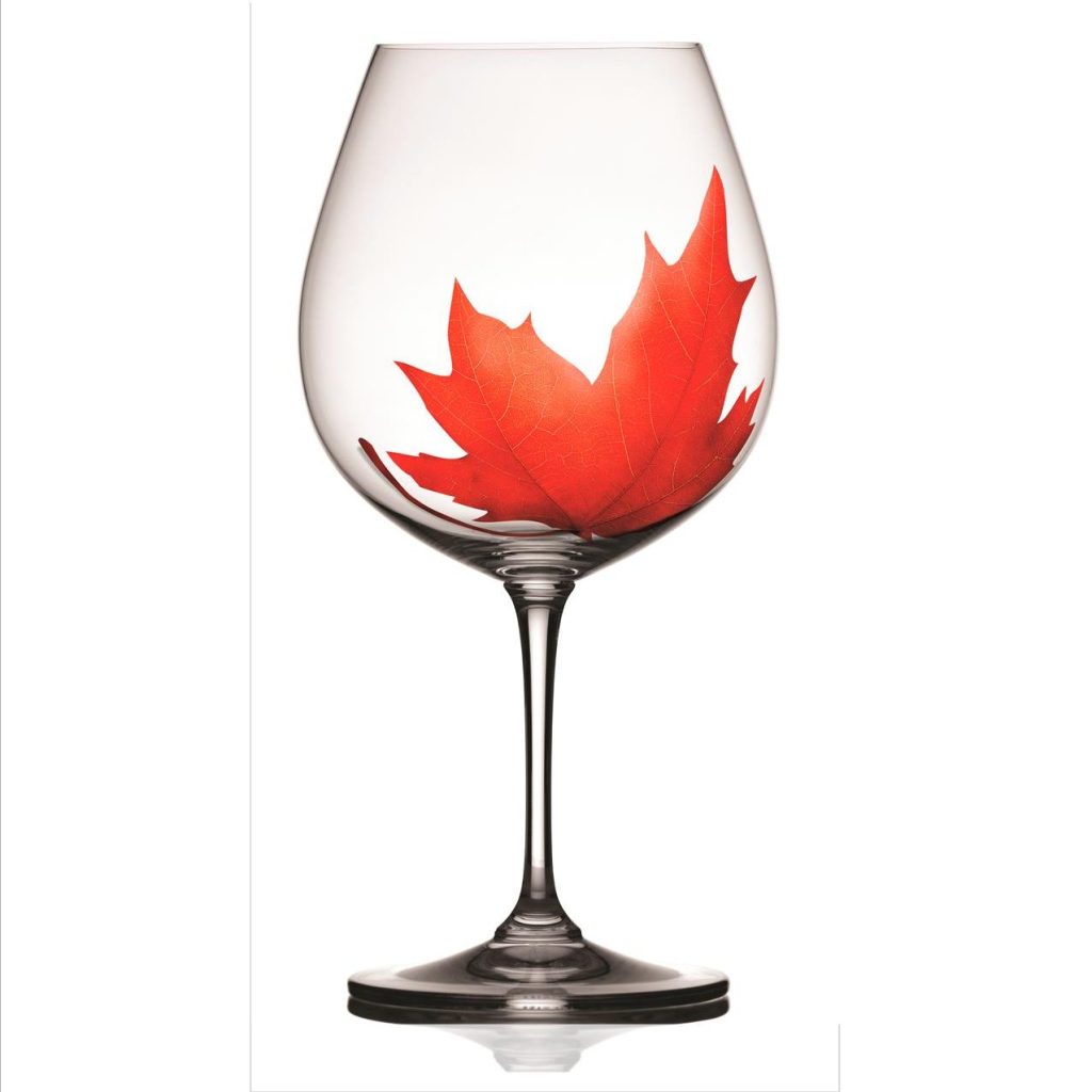 A wine glass with a red maple leaf design inside, symbolizing Canadian pride and the enjoyment of local wines.